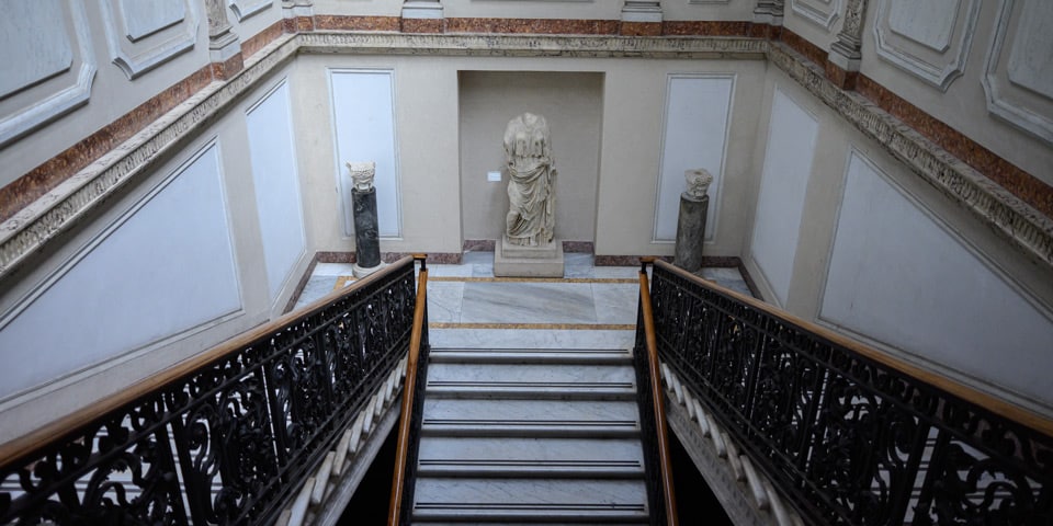 Marmortreppe mit schmiedeeisernem Geländer und antiker Statue im Museo Nazionale Romano in den Diokletiansthermen in Rom